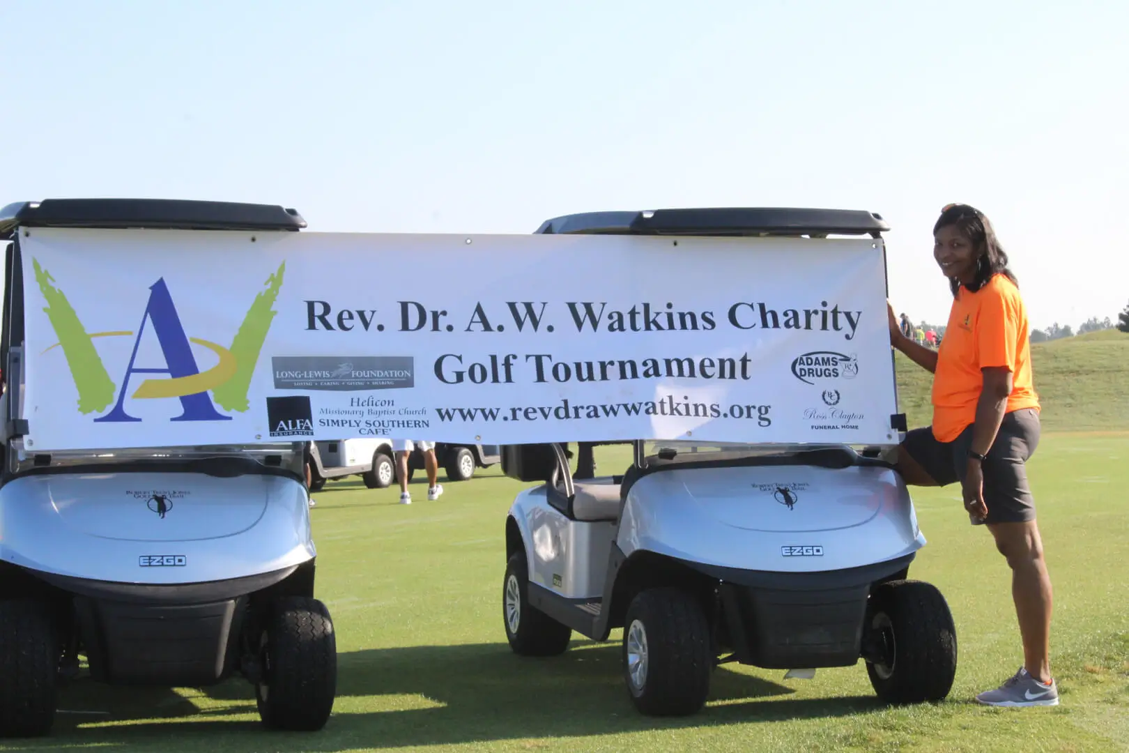 Golf carts parked under a charity golf tournament banner.