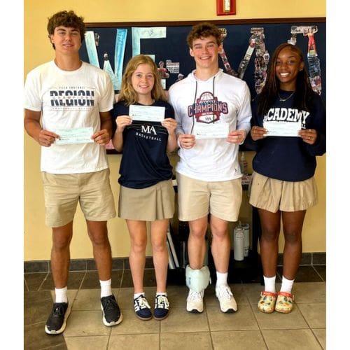 Four smiling students holding checks