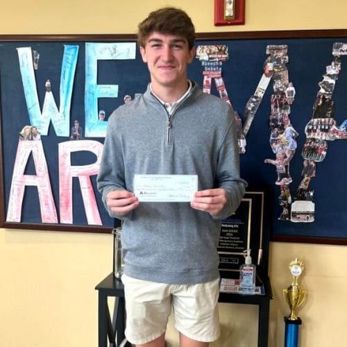 Student holding check by school display