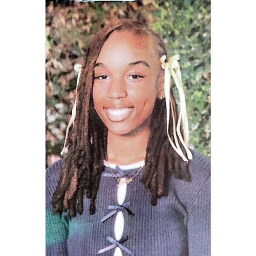 Smiling person with dreadlocks and ribbons