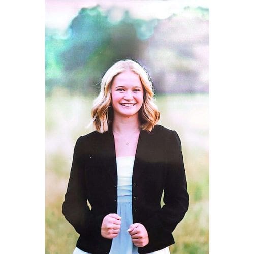 Smiling young woman in black jacket outdoors